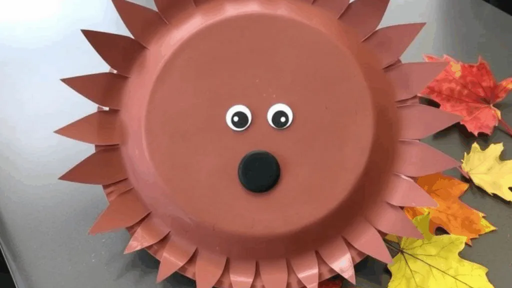 Fertiger Igel aus einem braunen Pappteller mit eingeschnittenen Stacheln und aufgemaltem Gesicht