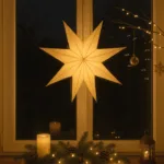 Warm leuchtendes Fenster zu Weihnachten mit Stern, Kerze und Tannenzweigen