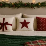 Weihnachtsdeko fürs Bett mit Kissen, Lichterkette und Tannenzweigen im warmen Licht