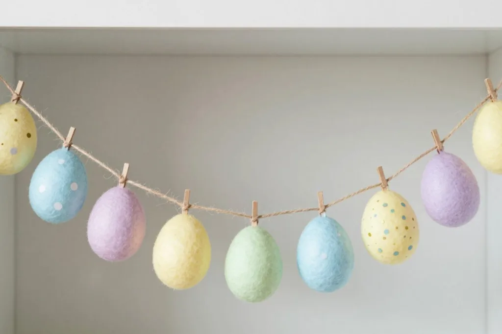 Osterdeko für die Vitrine mit pastellfarbener Eiergirlande im oberen Bereich