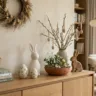 Moderne Osterdeko 2026 auf einem Eichen-Sideboard im Organic-Modern-Stil mit minimalistischen Keramikhasen, Weidenkätzchen und Naturmaterialien wie Moos und Holz.