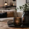 Moderne Wohnzimmerdeko aus Metall mit Kerzenhalter und schwarzer Metallvase auf Holztisch.
