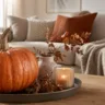 Herbstdeko für das Wohnzimmer mit Kürbis, Kerze und Naturmaterialien auf dem Couchtisch.