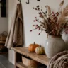 Herbstdeko für die Garderobe mit Vase, Trockenblumen, Kürbissen und Holzbank im hellen Flu