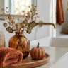 Herbstdeko für das Badezimmer mit Handtuch, Vase, Kürbis und warmen Naturtönen.