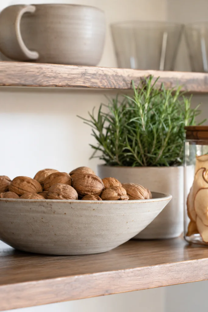 Herbstdeko für die Küche – 5 praktische Ideen ohne volle Arbeitsflächen Herbstdeko für die Küche mit Walnüssen, Rosmarin und getrockneten Apfelscheiben im offenen Regal.