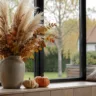 Herbstdeko für große Fenster mit Pampasgras, Kürbissen und natürlicher Fensterbank-Dekoration im warmen Wohnraum.