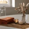 Herbstdeko für die Badewanne mit Holztablett, Kerze, Vase und warmen Naturtönen im Badezimmer.
