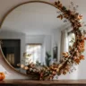 Herbstdeko für den Spiegel mit rundem Wandspiegel, Herbstgirlande, Trockenblumen und kleinen Kürbissen.