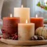 Moderne Herbstdeko mit Kerzen auf Holztablett mit Kürbis, Kastanien und warmem Licht im Wohnzimmer.