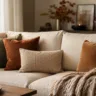 Herbstdeko fürs Sofa mit warmen Kissen, Strickdecke und ruhigen Naturtönen im gemütlichen Wohnzimmer.