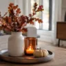 Moderne Herbstdeko für kleine Wohnzimmer mit Vase, Kerze und Kürbis auf dem Couchtisch.
