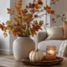 Moderne Herbstdeko im kleinen Wohnzimmer mit Vase, Herbstzweigen, Kerze und Kürbissen auf dem Couchtisch.