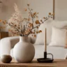 Minimalistische Herbstdeko fürs Wohnzimmer mit Vase, Herbstzweigen, Kerze und warmen Naturtönen.