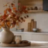 Moderne Herbstdeko für die Küche mit Vase, Herbstzweigen und Tablett in einer hellen, ruhigen Wohnküche.