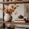 Moderne Herbstdeko fürs Regal mit Vase, Zweigen, Büchern und Kerzenlicht.