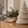 Moderne Weihnachtsdeko auf weißer Kommode mit großer Keramikvase, Tannenzweigen, Keramikbaum und Kerzenlicht.