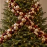 Weihnachtsbaum mit diagonaler Schmuckbahn aus roten und goldenen Kugeln, Schleifen und warmweißen Lichtern.