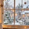 Weihnachtsdeko für die Fenster mit weißen Schneeflocken-Aufklebern, Holzsternen und warmen Lichterketten.