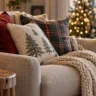 Weihnachtsdeko fürs Wohnzimmer mit festlichen Sofakissen, Strickdecke und beleuchtetem Weihnachtsbaum.
