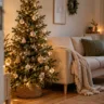 Kleines Wohnzimmer mit schmalem Weihnachtsbaum, warmen Lichterketten, beigem Sofa und gemütlicher Weihnachtsdekoration.