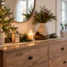 Weihnachtsdeko für die Kommode mit Tannengrün, Kerzen, Holzdeko und warmem Licht im Wohnzimmer.