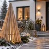 Moderne Weihnachtsdeko im Vorgarten mit beleuchtetem Holzbaum neben einem verschneiten Gartenweg.
